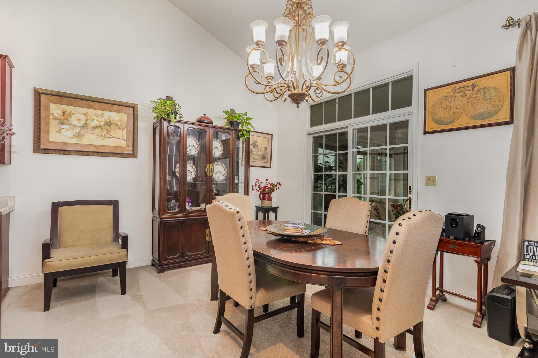 Dining room with an oval wood table, beige chairs, china cabinet, and ornate chandelier.