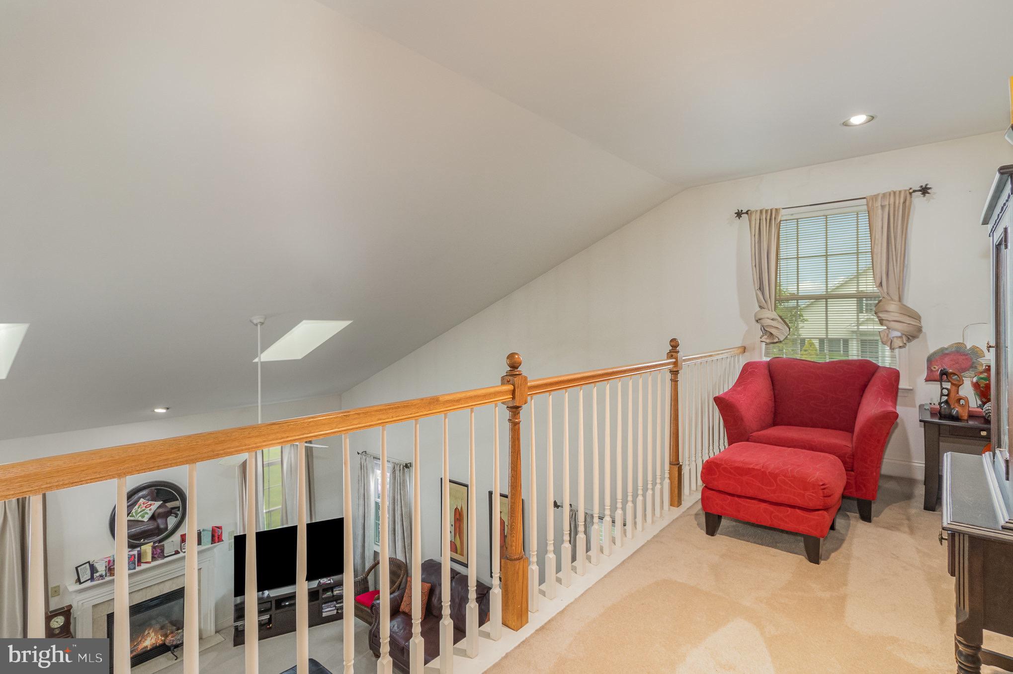 Upstairs loft landing with a red armchair and railing overlooking the living room.