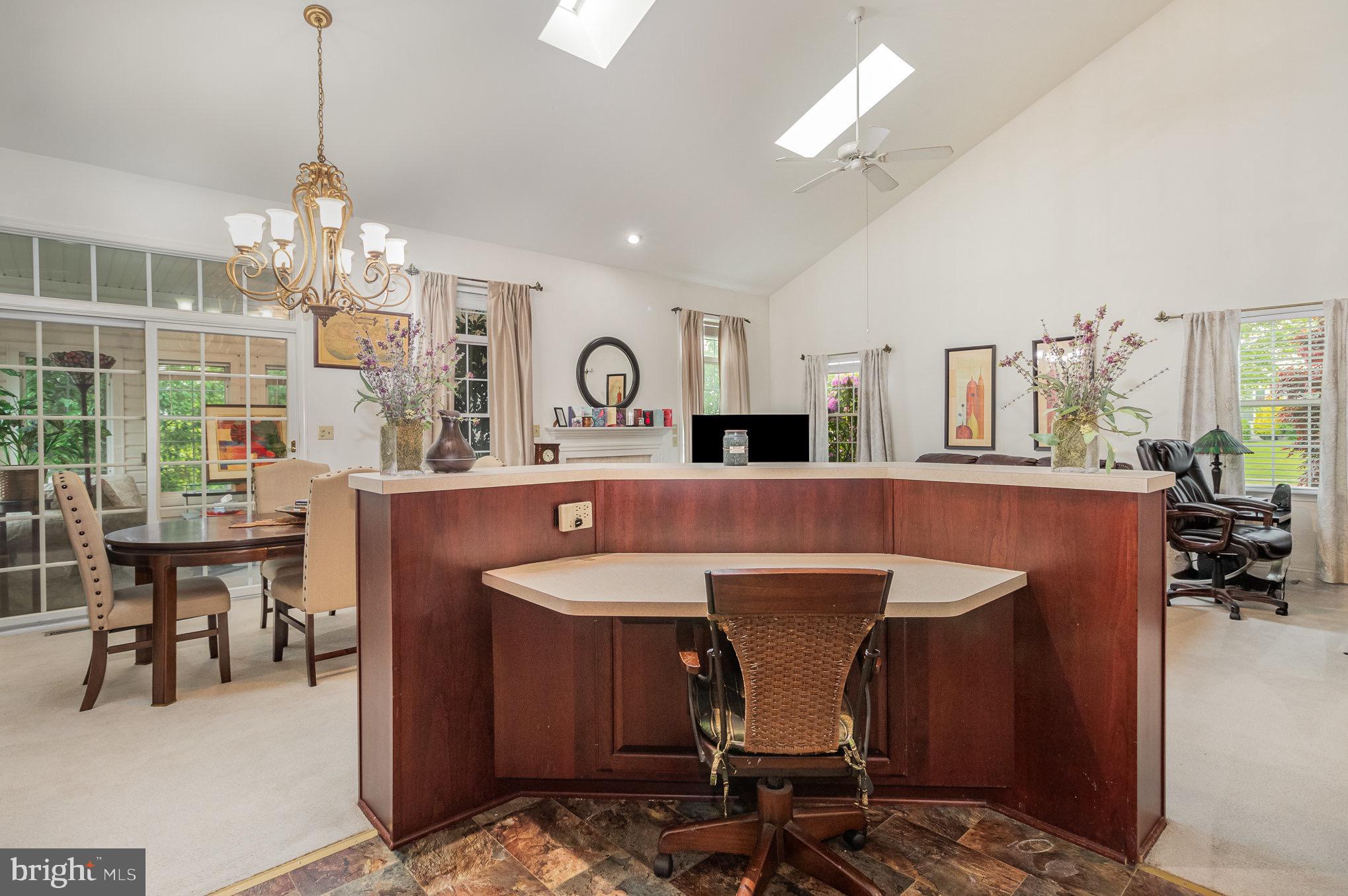 Living room with a large curved wood desk, vaulted ceiling, skylights, and chandelier.