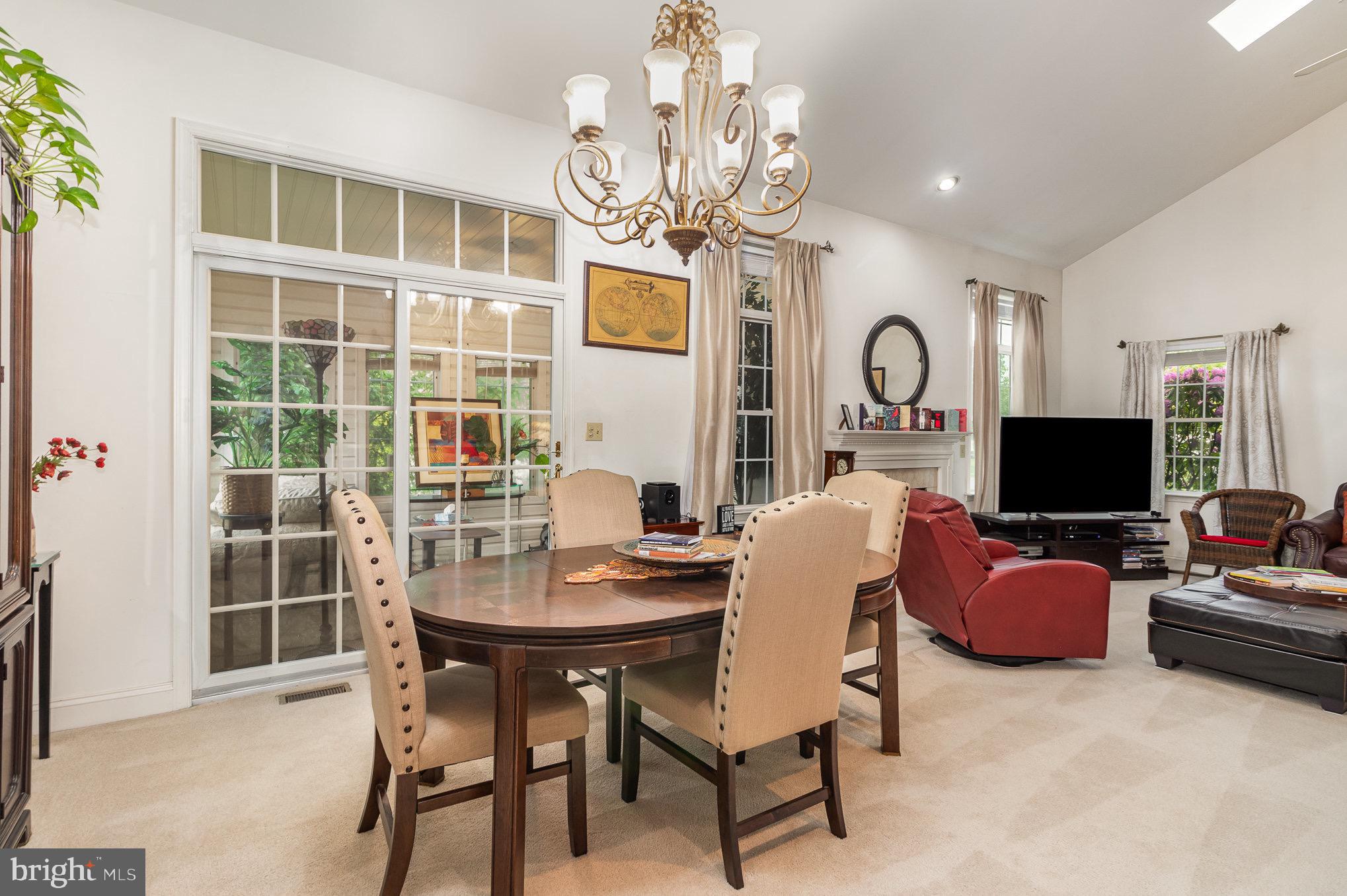 Furnished living and dining area with a round table, red leather seating, and glass doors to a sunroom.