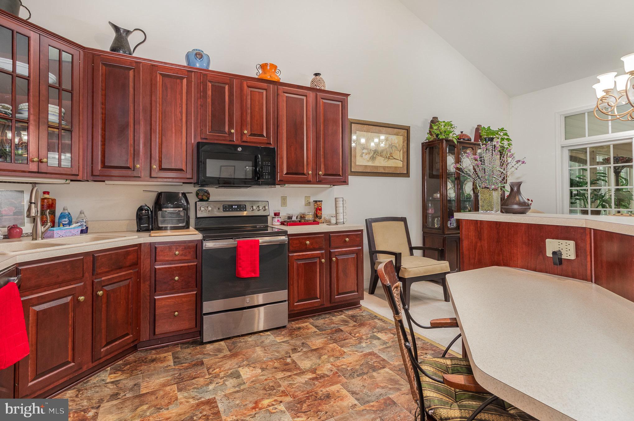 Kitchen with dark wood cabinets, stainless-steel range, and a large island with seating.