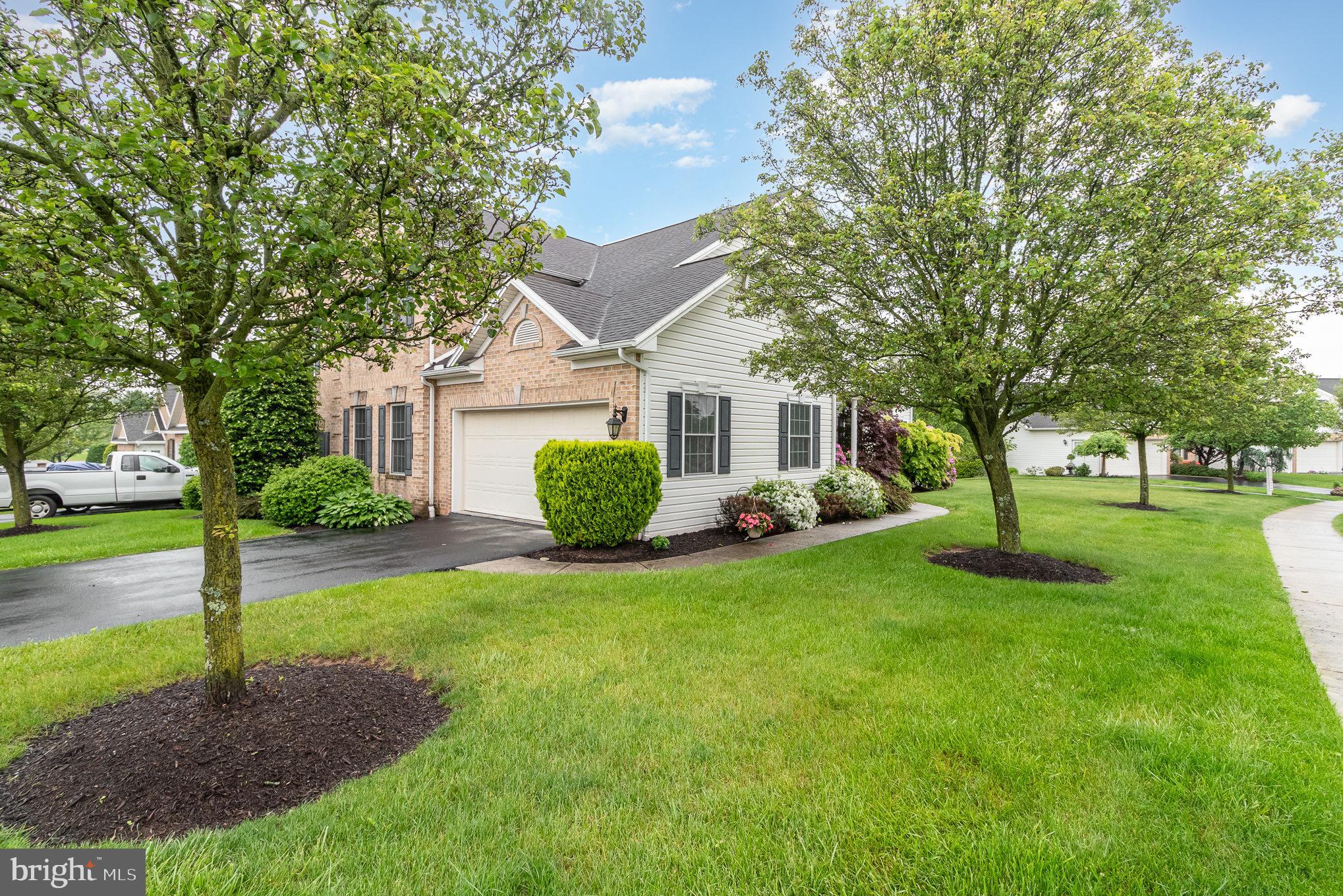 Home with brick front, attached garage, landscaped lawn, and mature shade trees.
