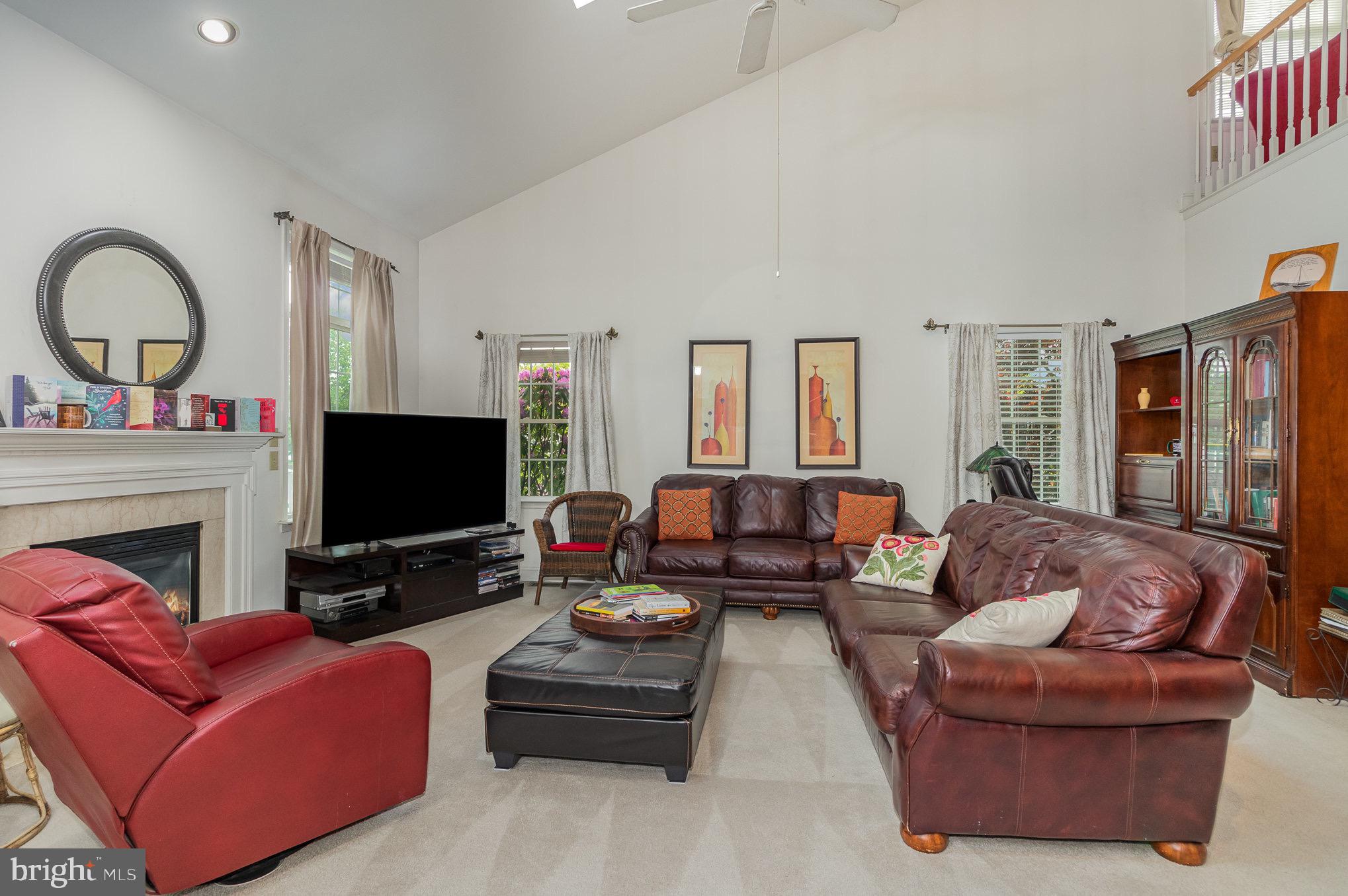 Living room with vaulted ceiling, white fireplace, leather seating, and an open second-floor railing.