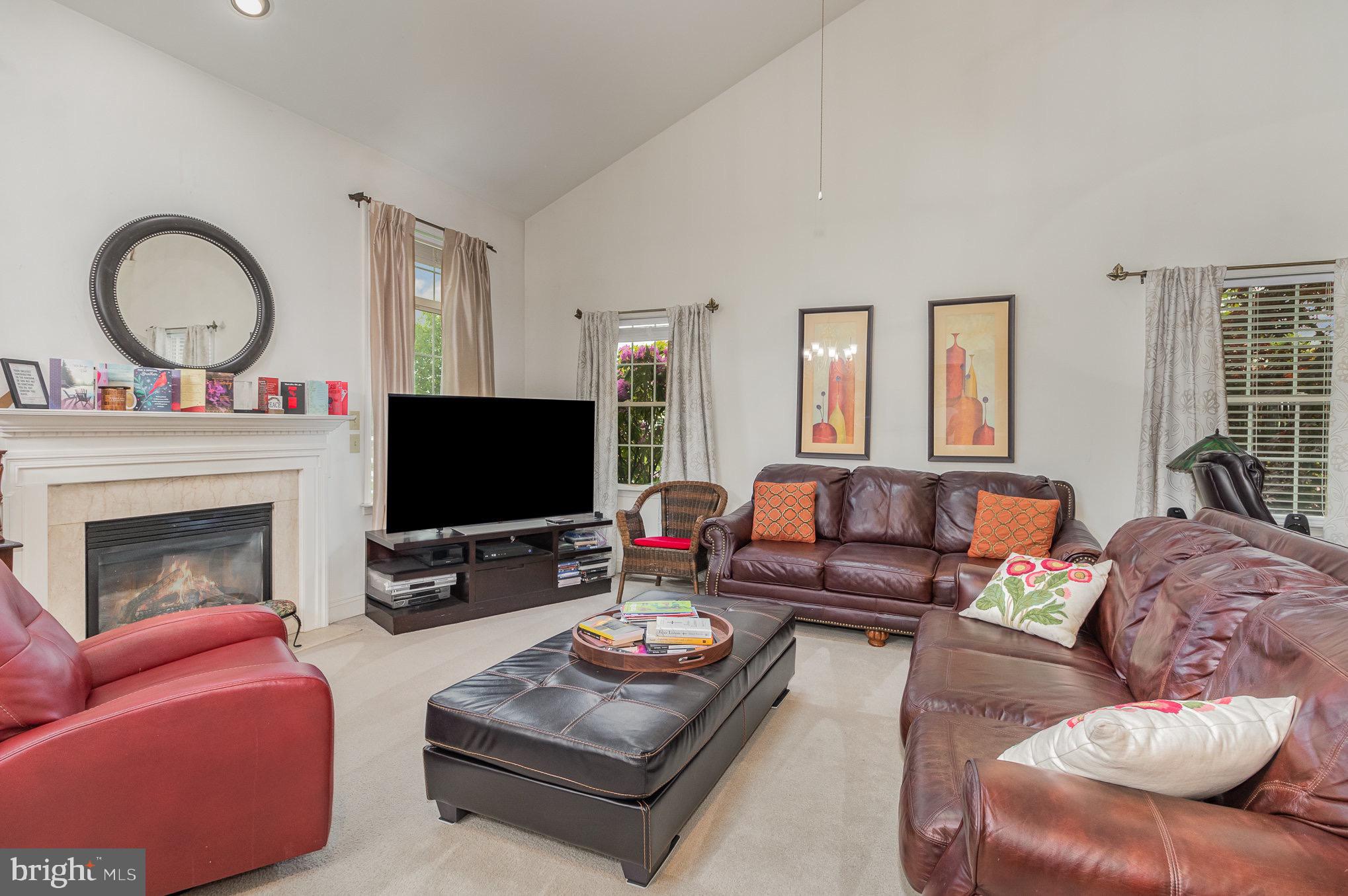 Furnished living room with a fireplace, vaulted ceiling, and brown leather sofas.