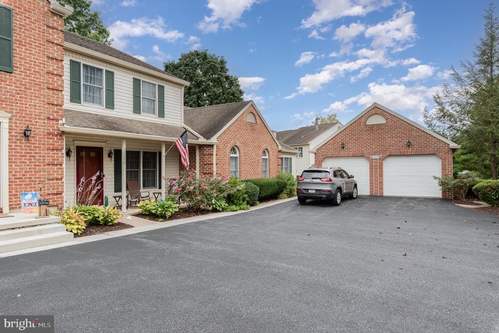 Brick-and-siding home with a covered porch, landscaped flower beds, and an attached two-car garage.