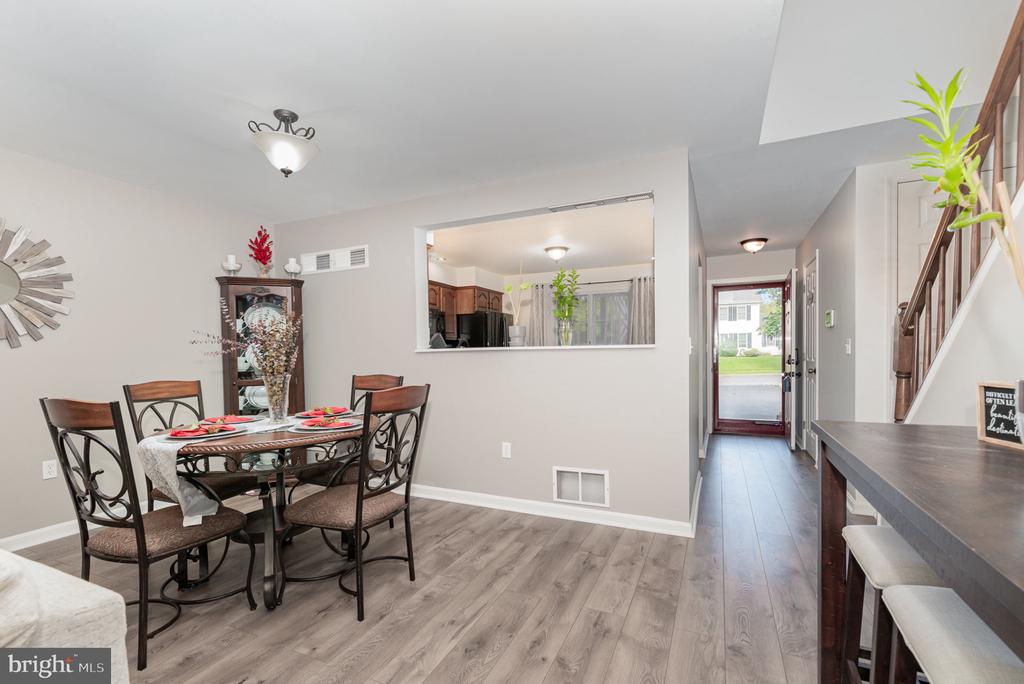 Dining area with a round table, kitchen pass-through, and entry hall beside the staircase.