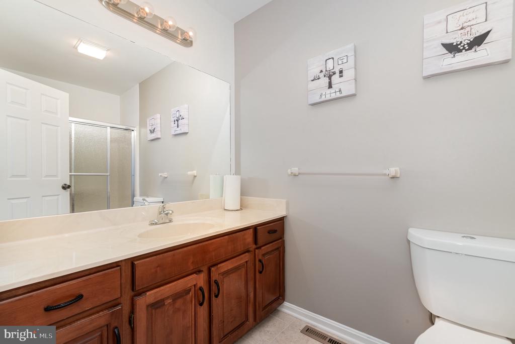 Bathroom with a long wood vanity, large mirror, glass shower, and toilet.