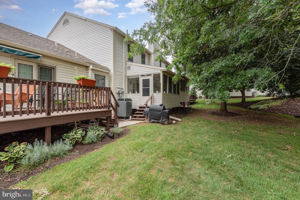 Townhouse rear exterior with a raised deck, screened porch, and grassy yard.