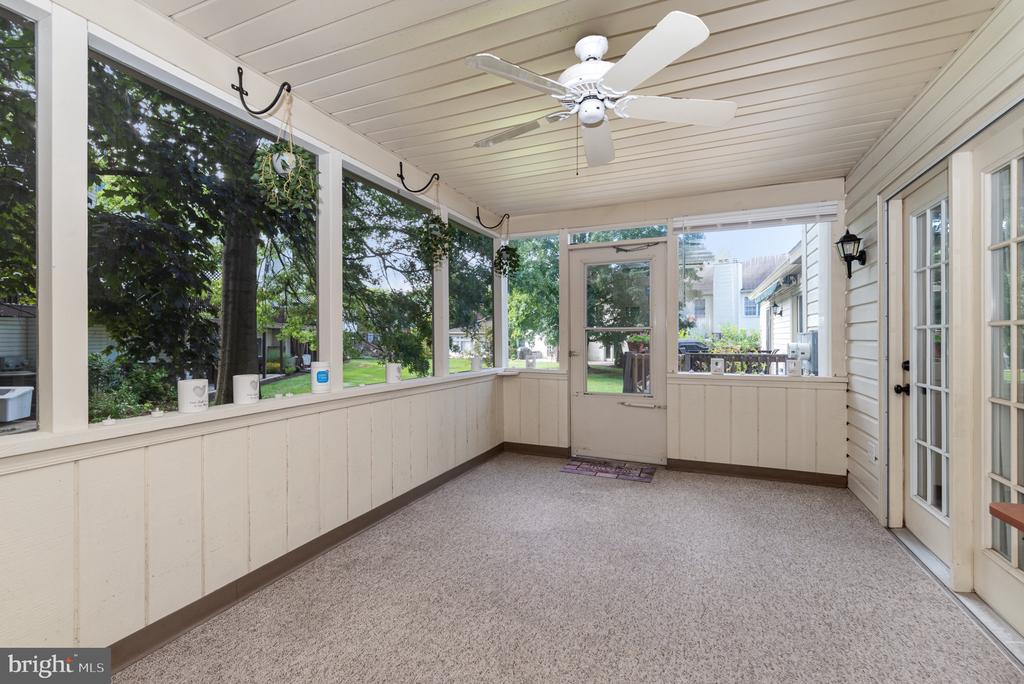 Enclosed porch with carpeted floor, screened windows, ceiling fan, and glass doors to the yard.