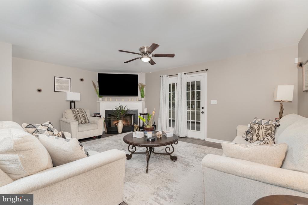 Living room with a fireplace, television, pale seating, and white French doors.