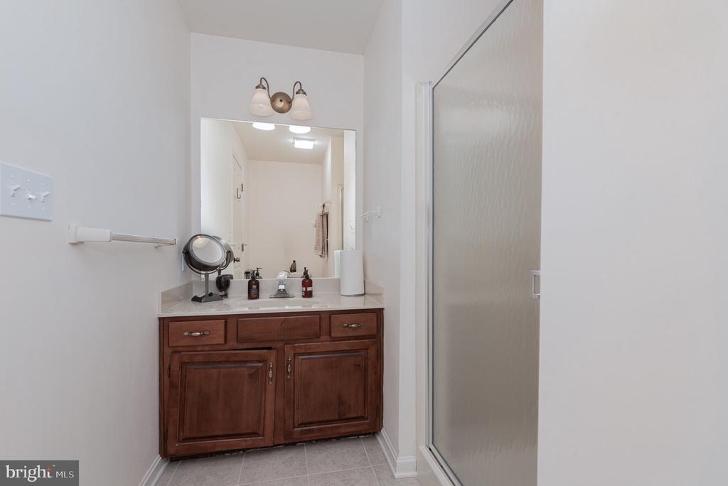Bathroom vanity with dark wood cabinets beside a frosted-glass shower.