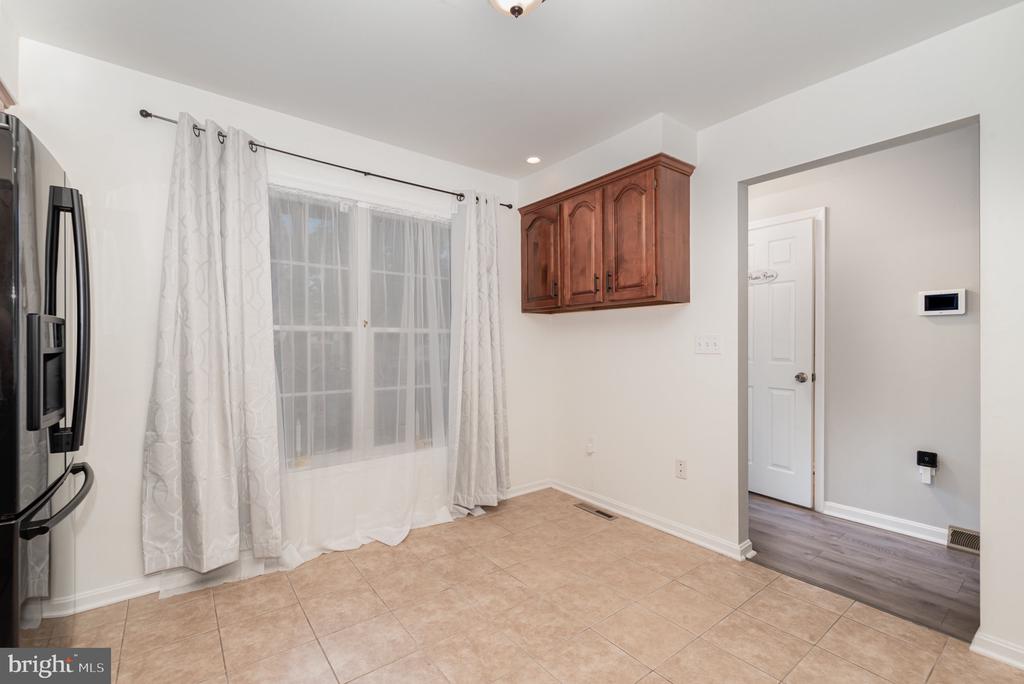 Kitchen with beige tile floors, a stainless-steel refrigerator, and a large curtained window.