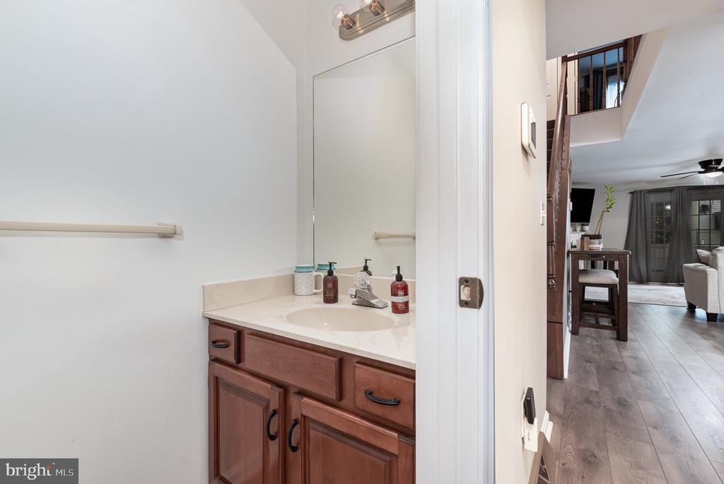 Bathroom vanity with wood cabinets and a doorway opening toward the dining and living areas.