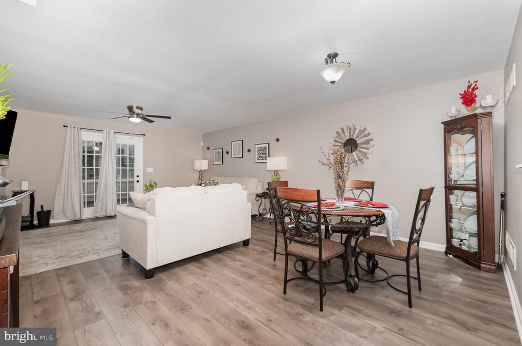 Open-plan living and dining room with a white sofa, round table, and French doors.