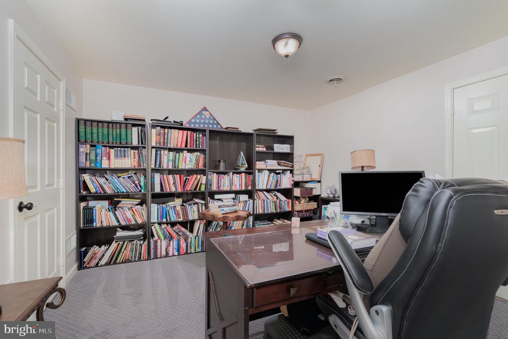 Home office with book-filled shelves, a computer desk, and a large black chair.
