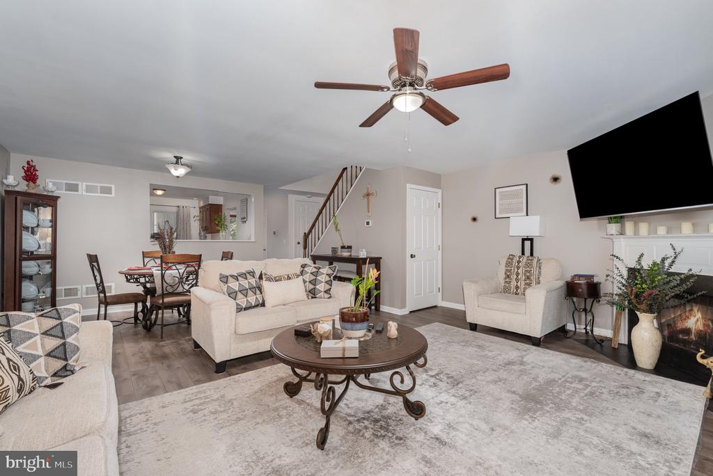 Furnished living room with a cream sofa, round coffee table, dining area, and staircase.