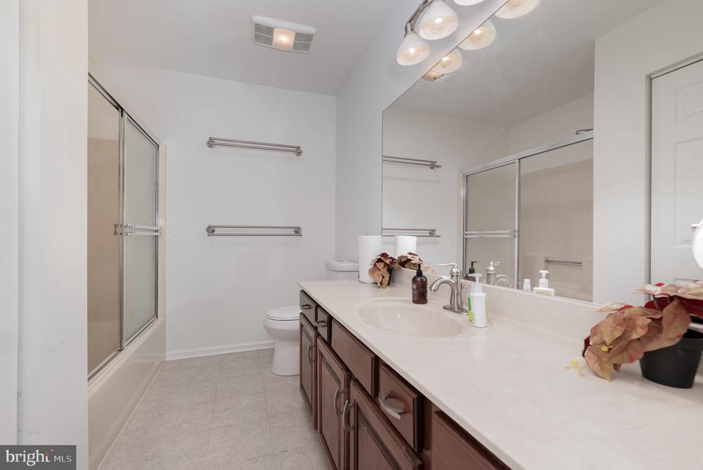 Bathroom with a long dark wood vanity, large mirror, and glass-enclosed shower.