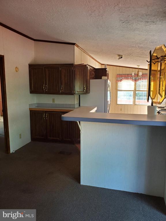 Kitchen with dark wood cabinets, a peninsula counter, and a windowed dining area.