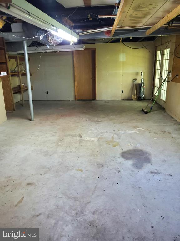 Unfinished basement with a concrete floor and exposed ceiling joists.