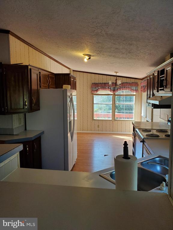 Kitchen with dark wood cabinets, electric range, and a large curtained window.