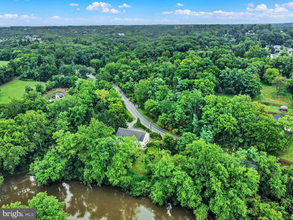 Aerial view of a wooded property with a house, winding road, and river.
