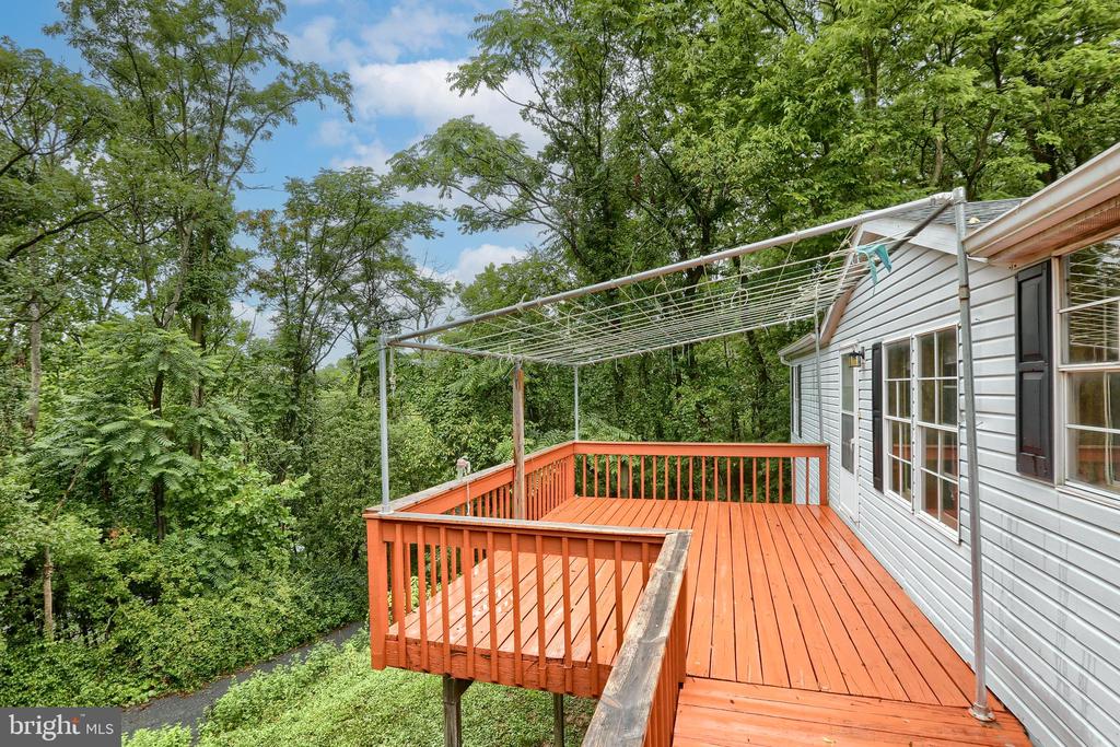 Elevated orange-red deck beside a white-sided home, surrounded by dense trees.