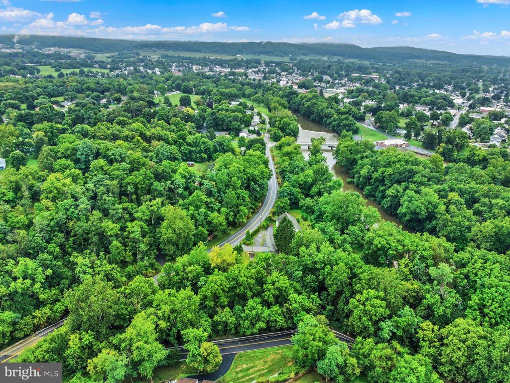 Aerial view of wooded surroundings, with a winding river and nearby town.