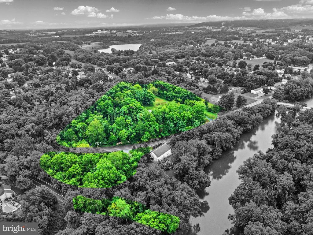 Aerial view of wooded property parcels highlighted beside a river and railroad tracks.