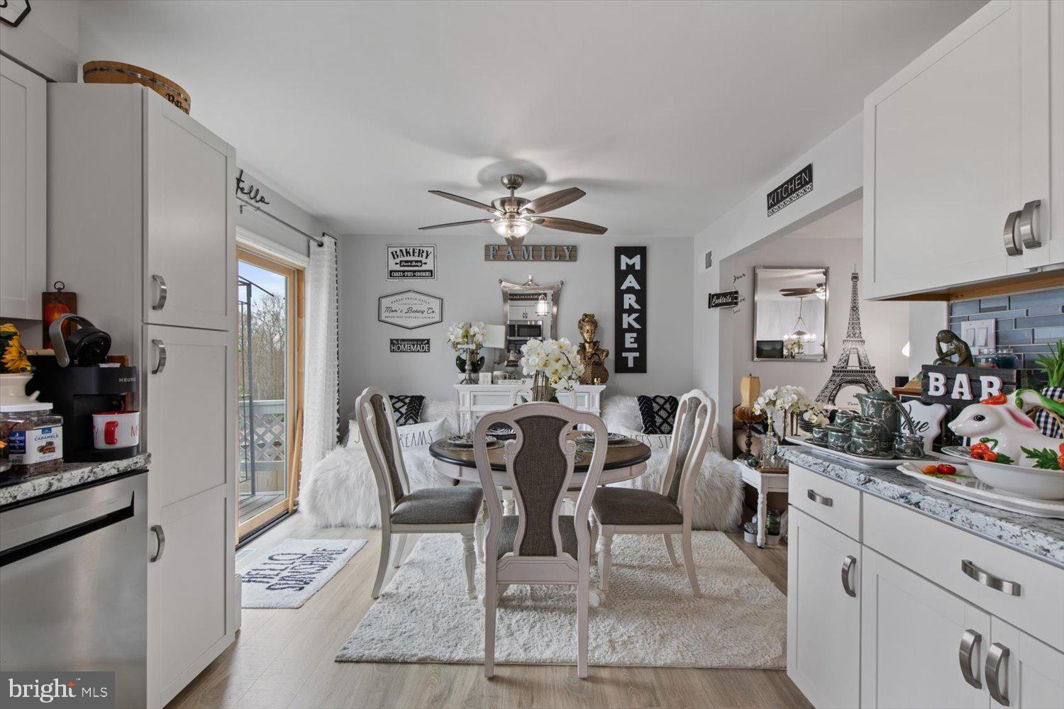 Kitchen and dining area with white cabinetry, blue tile backsplash, and a round table beside a sliding glass door.
