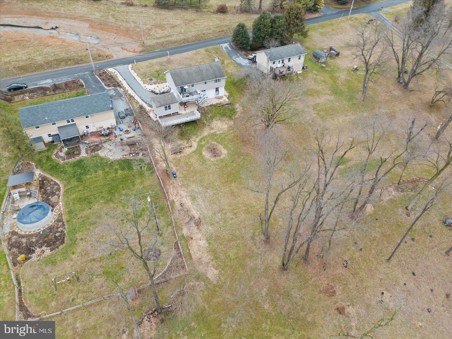 Aerial view of a large property with several homes, a swimming pool, and open land.