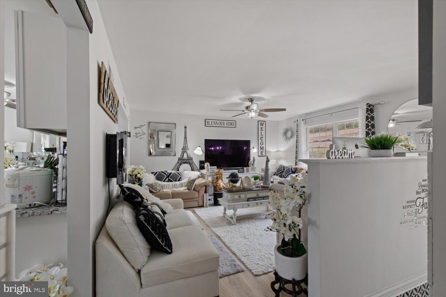 Furnished living room with white sofas, black-and-white accents, a TV, and a window.