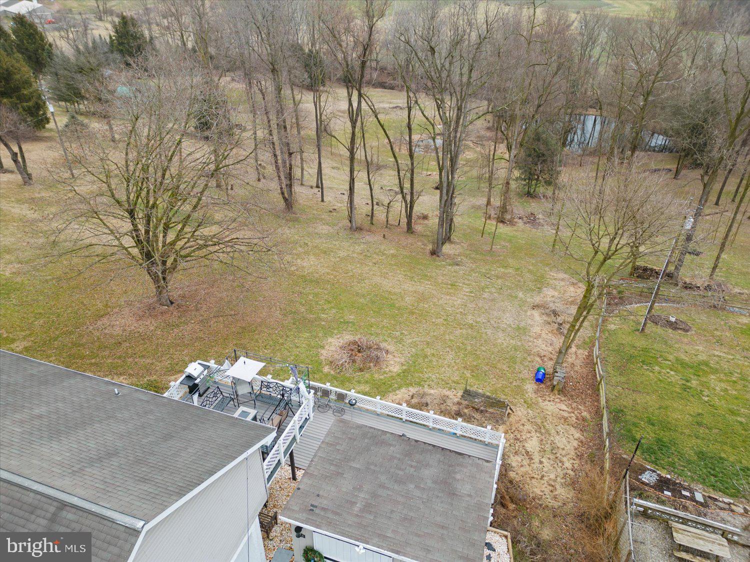 Aerial view of a wooded backyard and raised deck behind the home.
