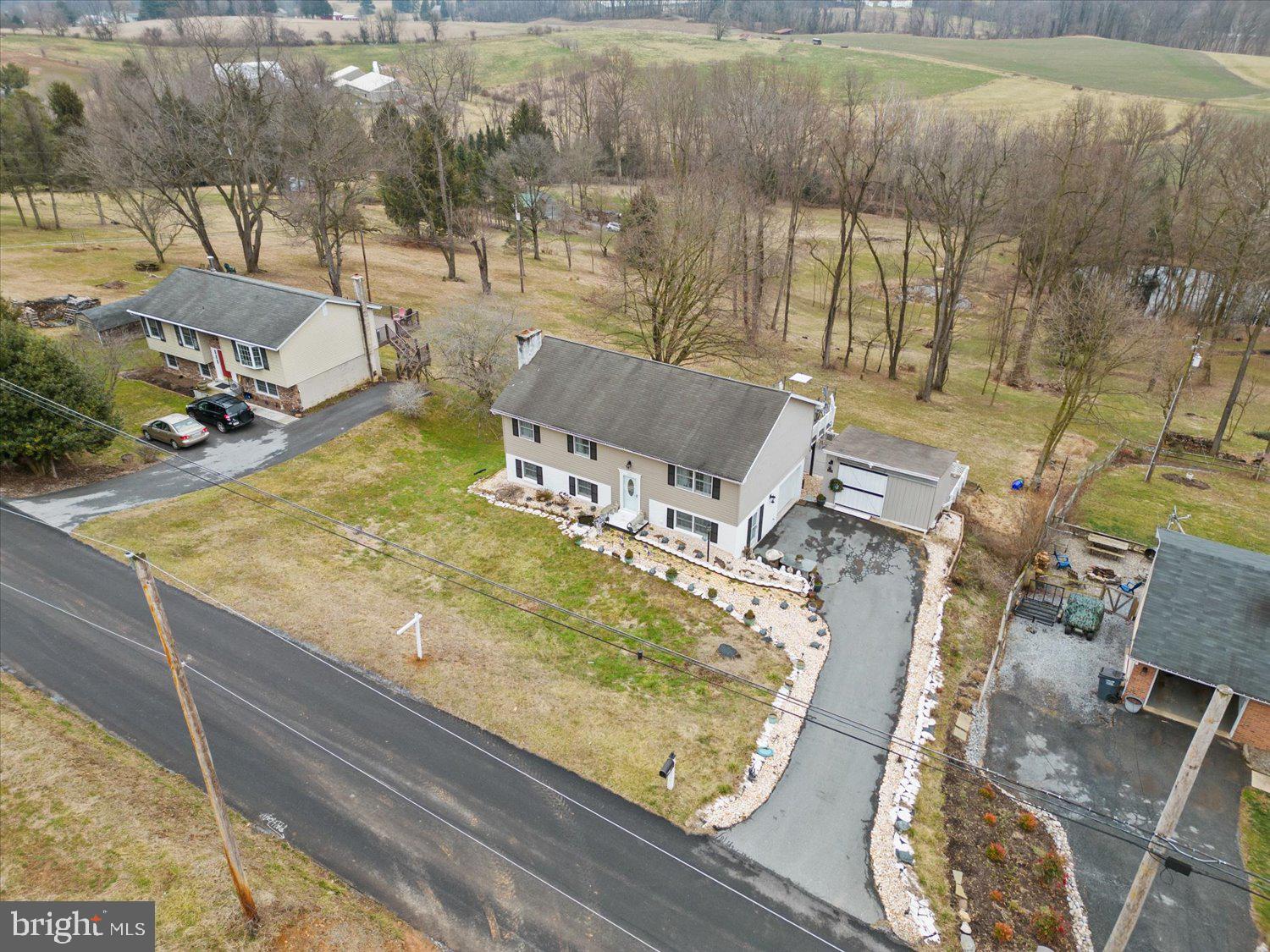 Aerial view of a beige split-level home with a long driveway and attached garage.