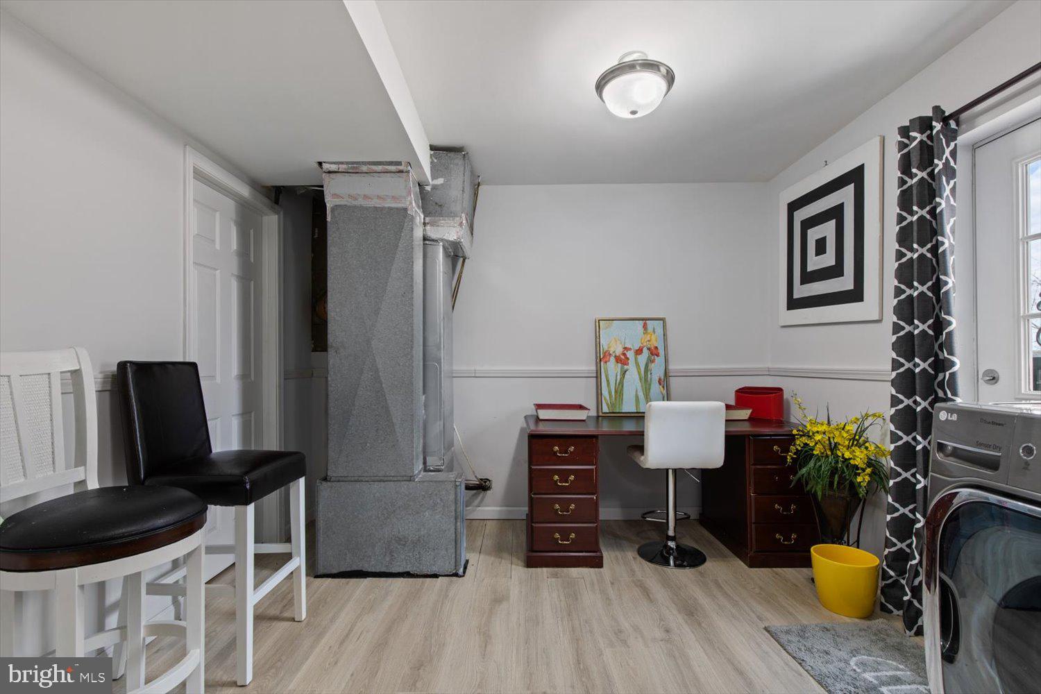 Laundry area and home office with a desk, washer and dryer, and prominent gray masonry column.