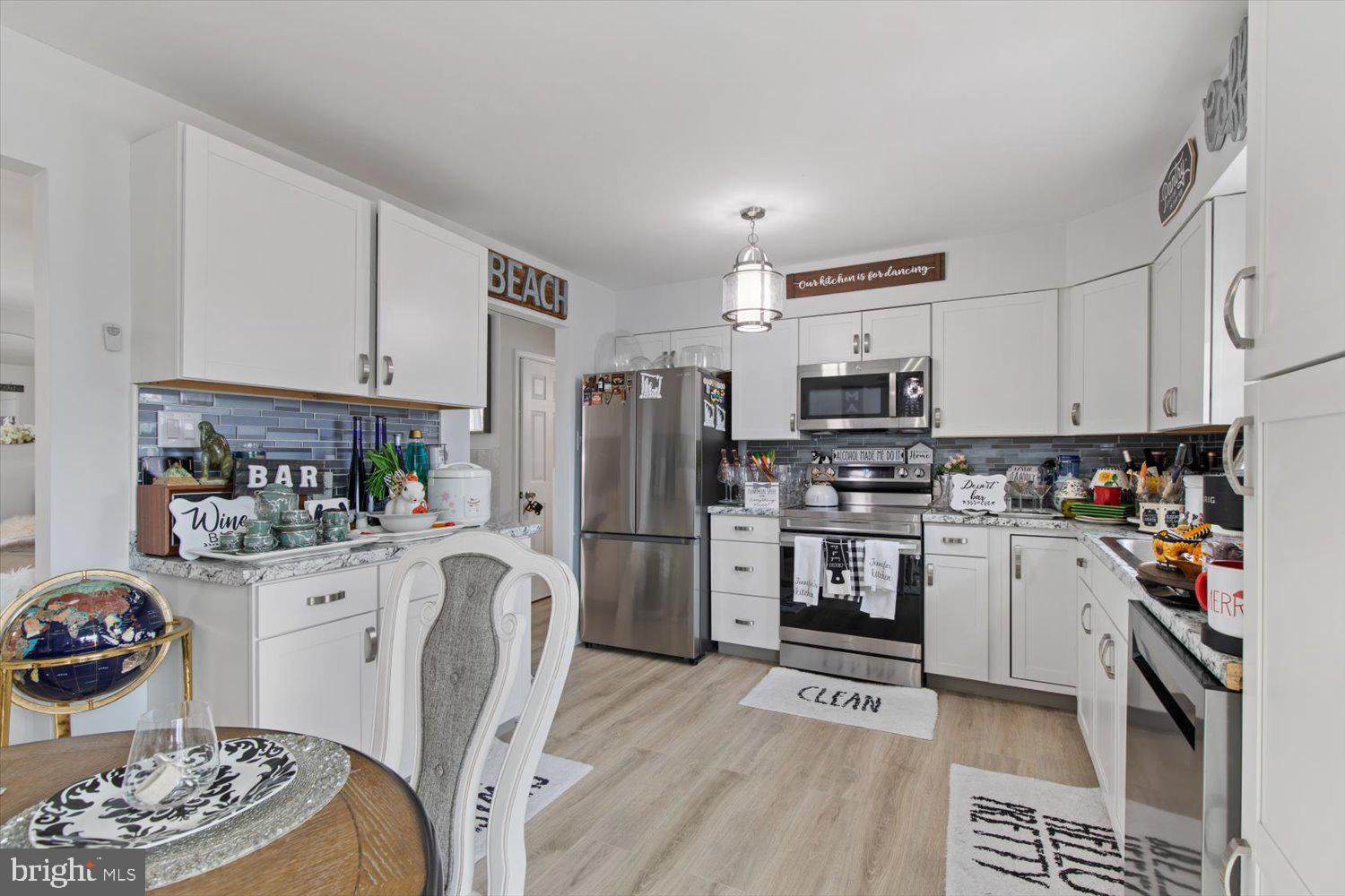 Kitchen with white cabinets, stainless steel appliances, and a blue-gray tile backsplash.