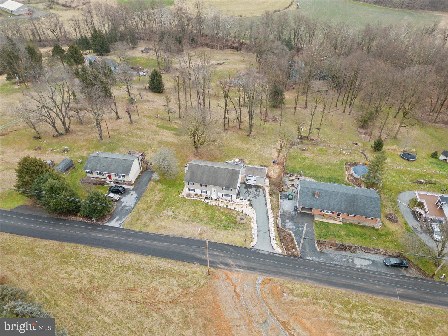 Aerial view of a two-story home with a long driveway and expansive wooded yard.