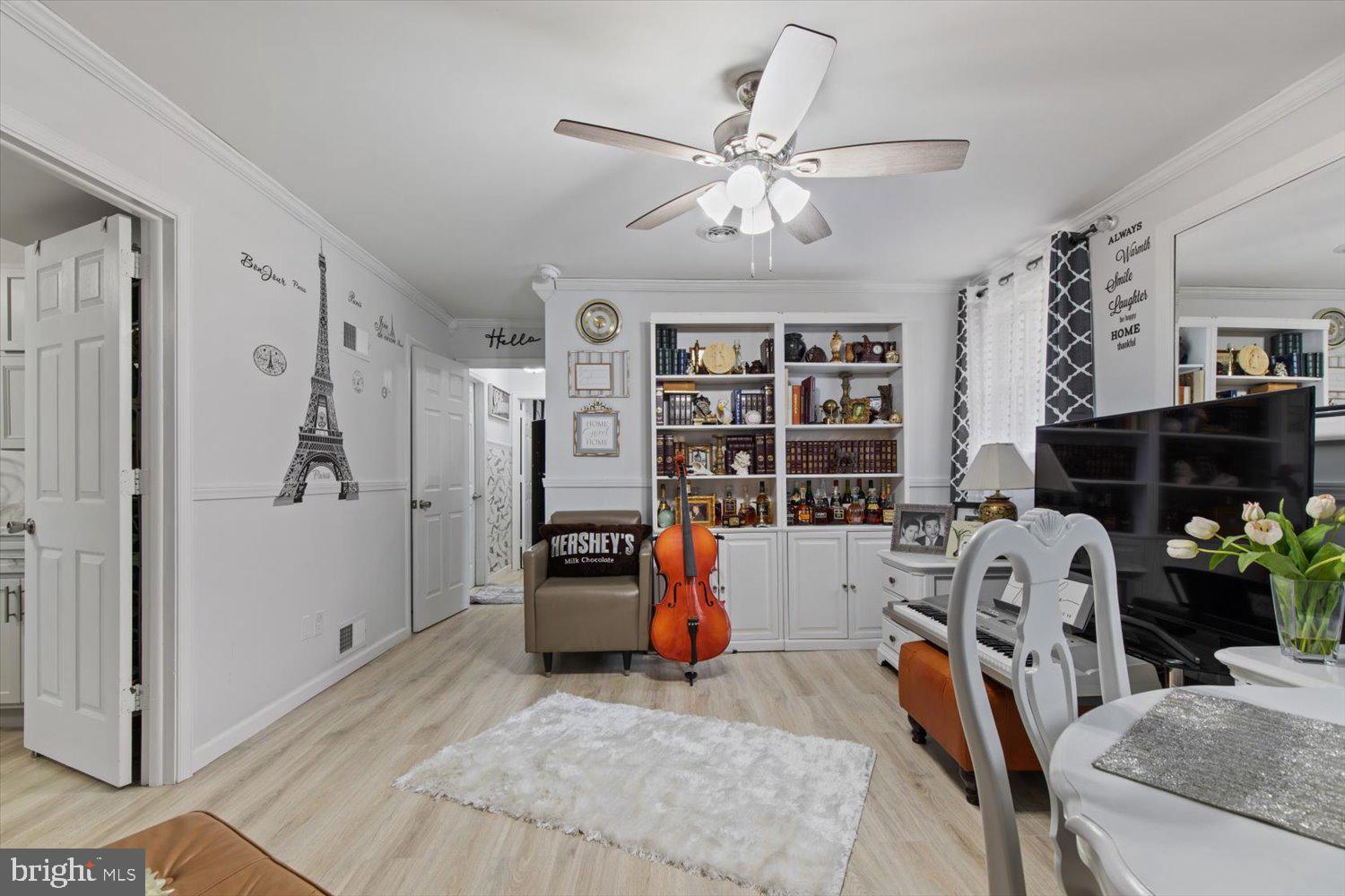 Living room with built-in bookshelves, a cello, piano, and television.