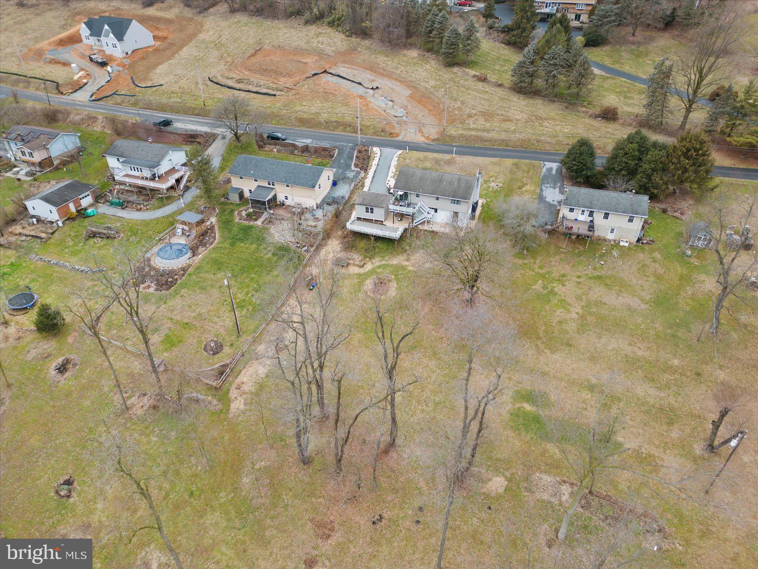 Aerial view of a large property with a house, graded ground, open lawn, and leafless trees.