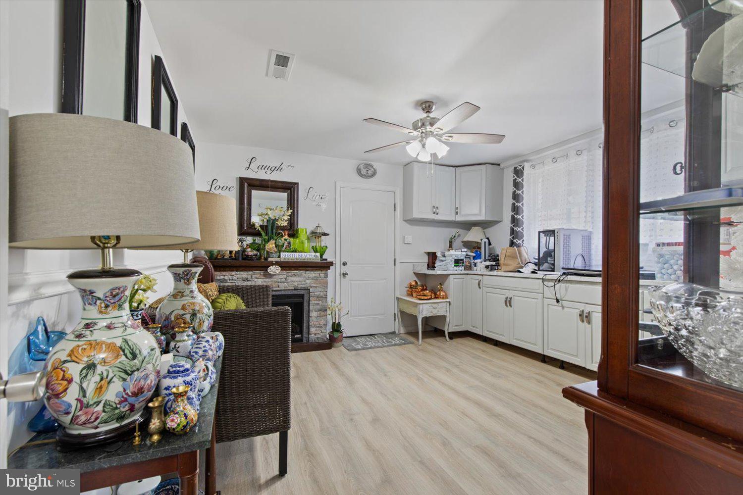 Kitchen and sitting area with white cabinets, stone fireplace, and decorative porcelain vases.