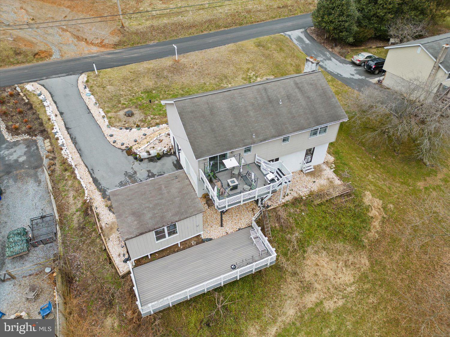 Aerial view of a home with a large raised deck, smaller deck, and detached outbuilding.