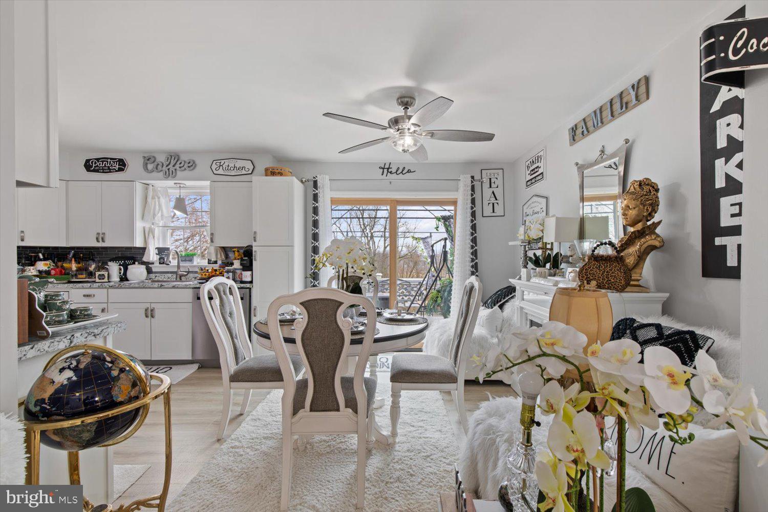 Open-plan kitchen and dining area with white cabinets, round table, and sliding glass doors.