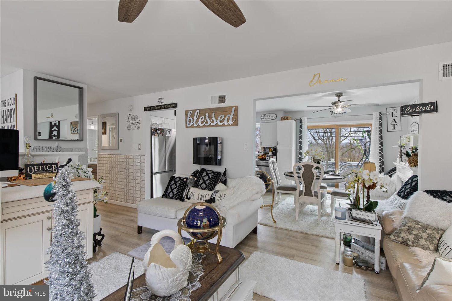 Open-plan living and dining room with white sofas, a bright window, and a decorated Christmas tree.