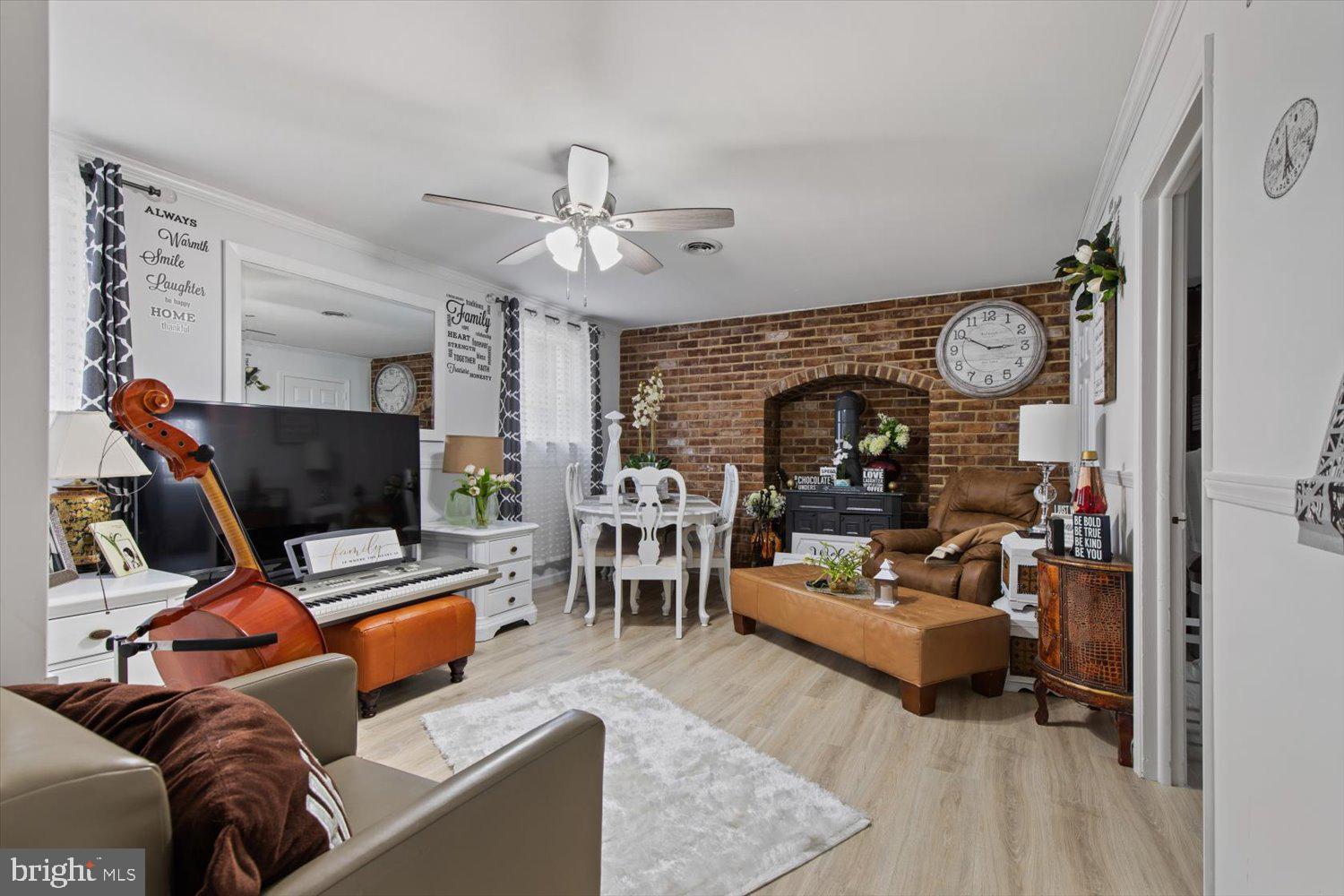 Living room with a brick fireplace, brown leather seating, and a piano beside a cello.