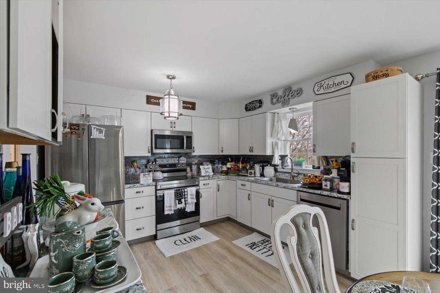 Kitchen with white cabinets, stainless steel appliances, granite counters, and a sink beneath a window.