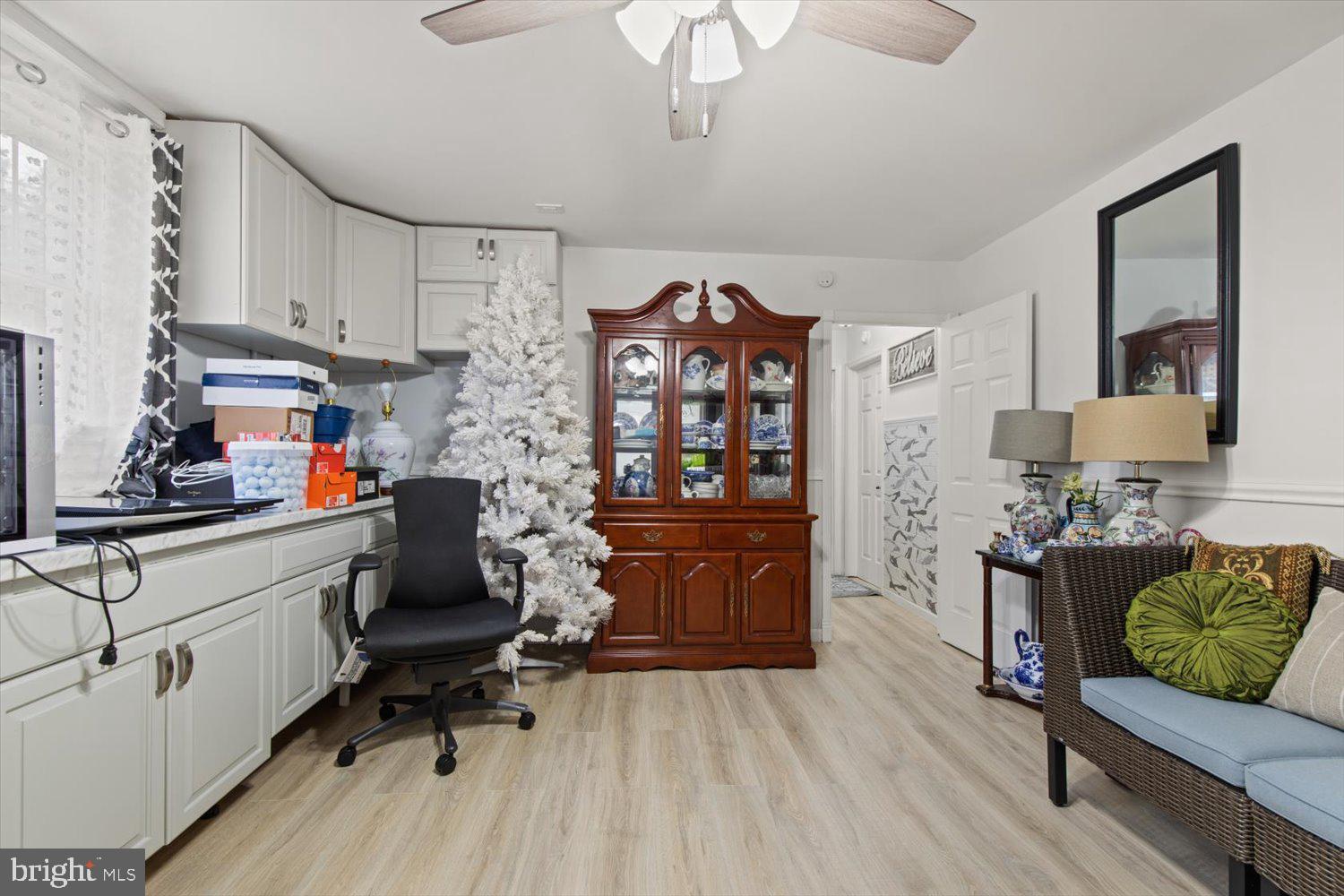 Cabinet-lined room with a white Christmas tree, china cabinet, and wicker seating.