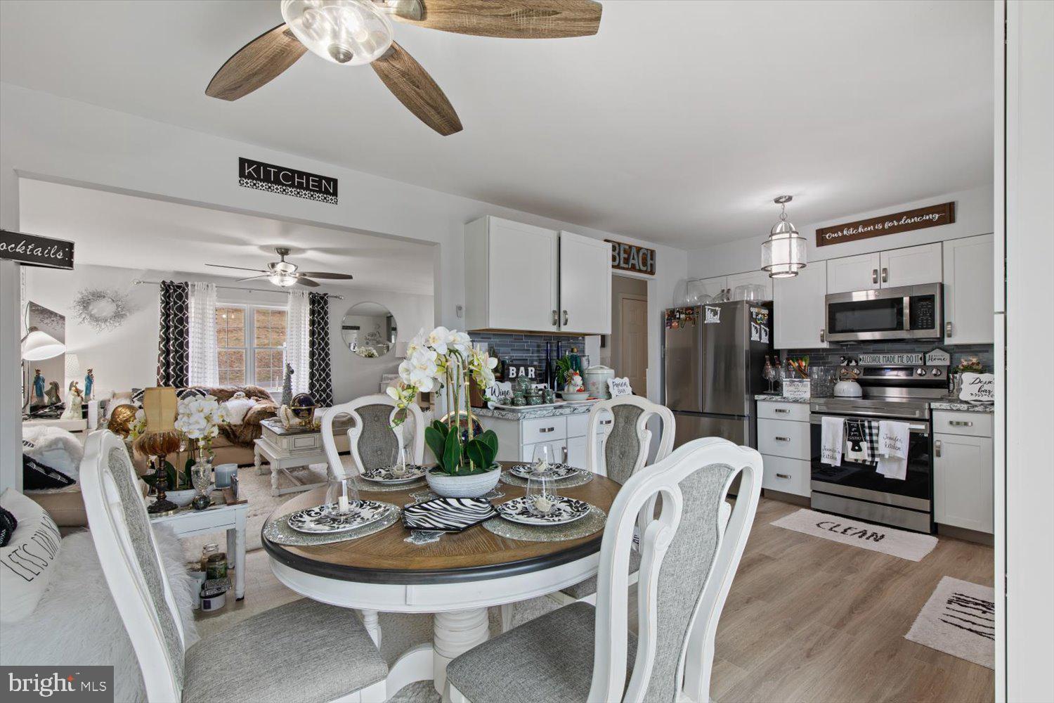 Open kitchen and dining area with white cabinetry, stainless appliances, and a set dining table.