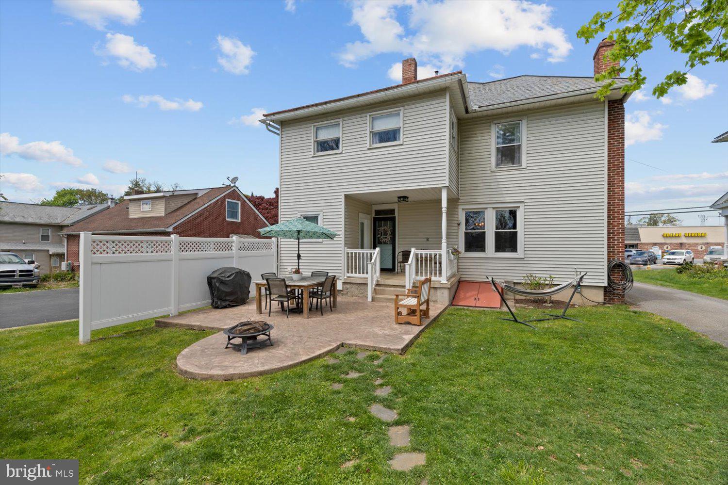 House backyard with a fenced patio, outdoor dining set, fire pit, and hammock.