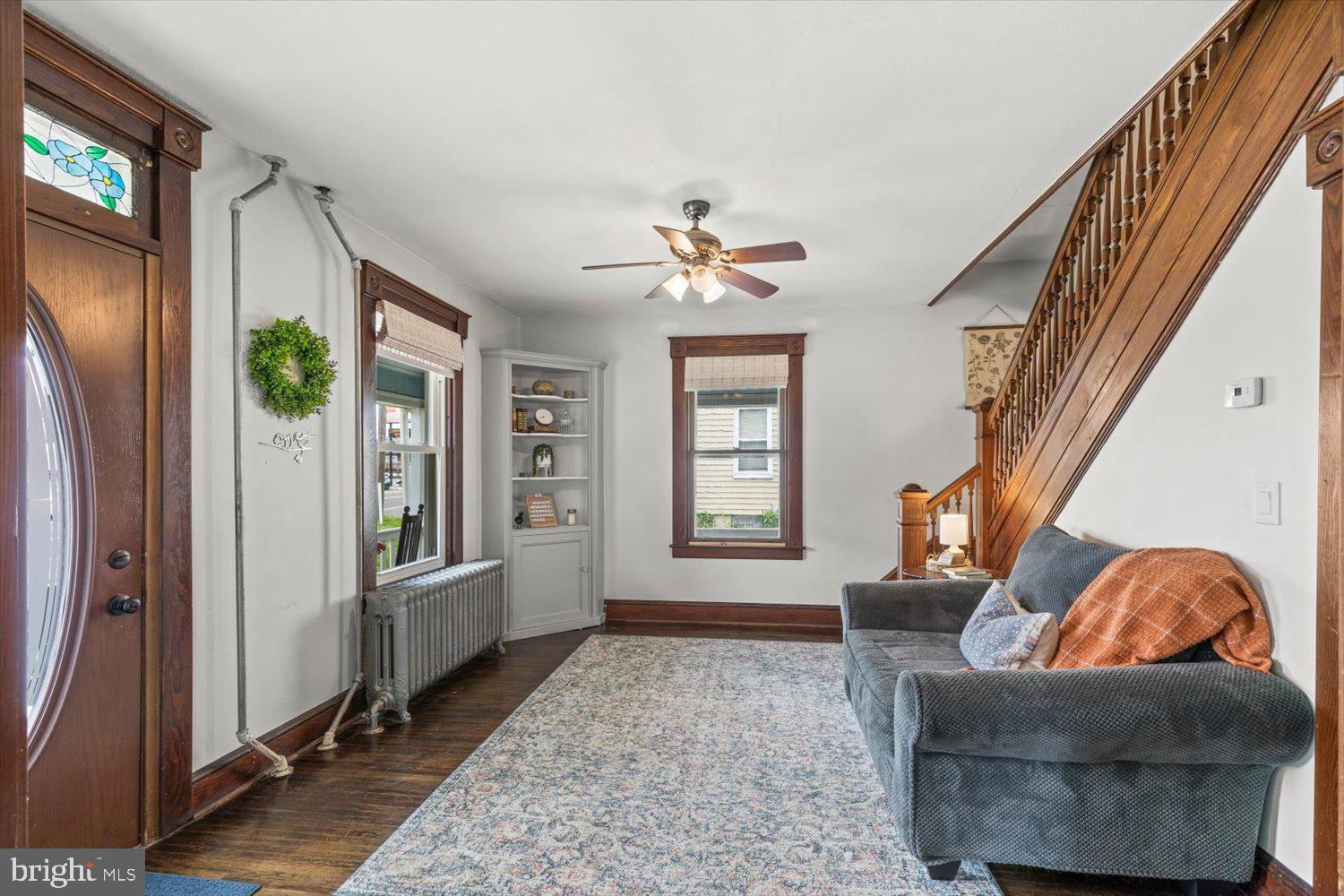 Living room with a stained-glass entry door, built-in shelves, and a wooden staircase.