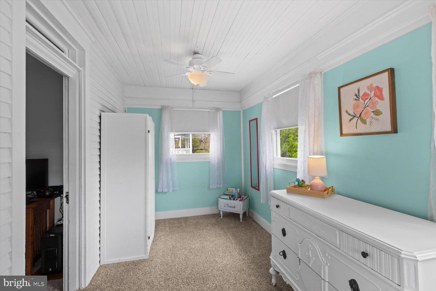 Bedroom with turquoise walls, white beadboard ceiling, and a large white dresser.
