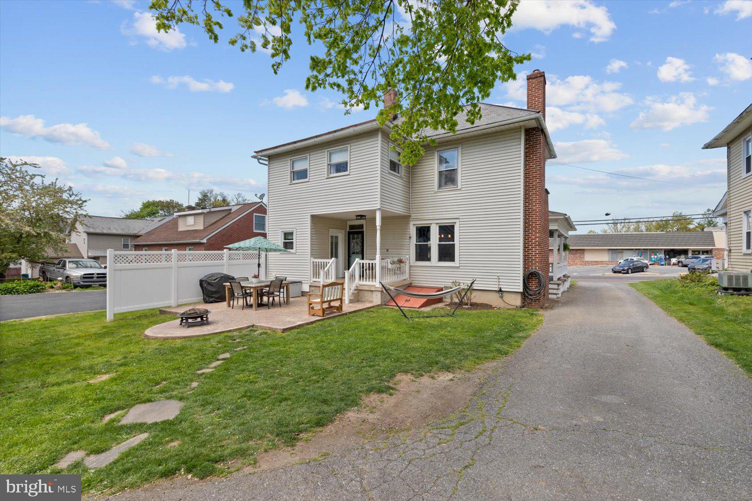 Rear exterior of a two-story home with a fenced patio and outdoor seating.